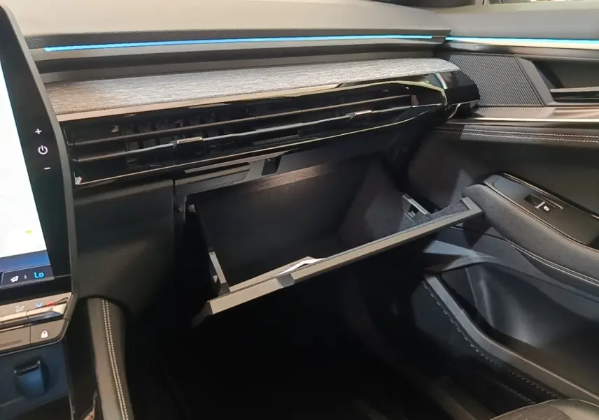 Intérieur Renault Austral 2023, vue côté passager sur la boîte à gants ouverte et tableau de bord noir avec inserts bois.