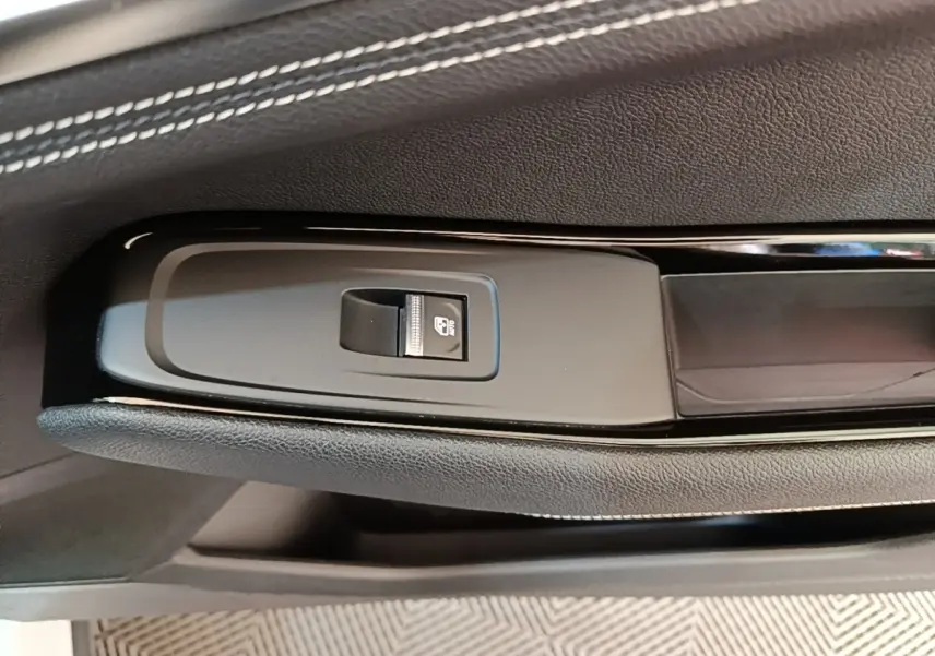 Gros plan sur la commande de verrouillage électrique sur la porte intérieure noire du Renault Austral blanc.
