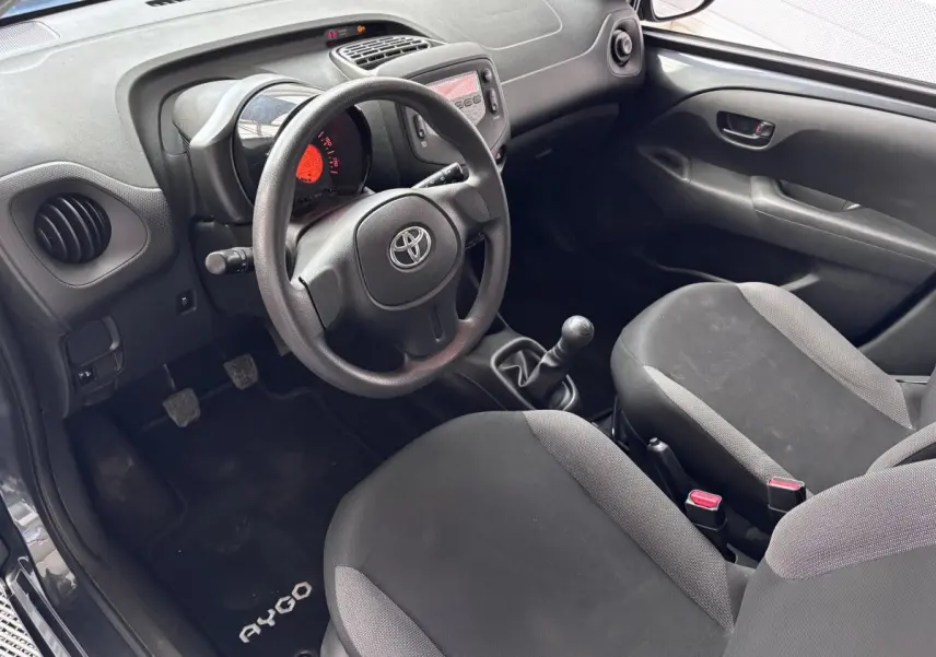 Intérieur avant droit de la Toyota Aygo 1.0 VVT-i x-black 2020, volant, tableau de bord et sièges noirs visibles.