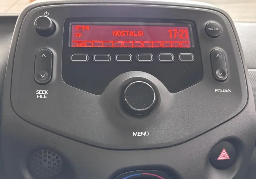 Gros plan sur l’autoradio noir de la Toyota Aygo 2020, affichant la radio FM sur fond rouge.