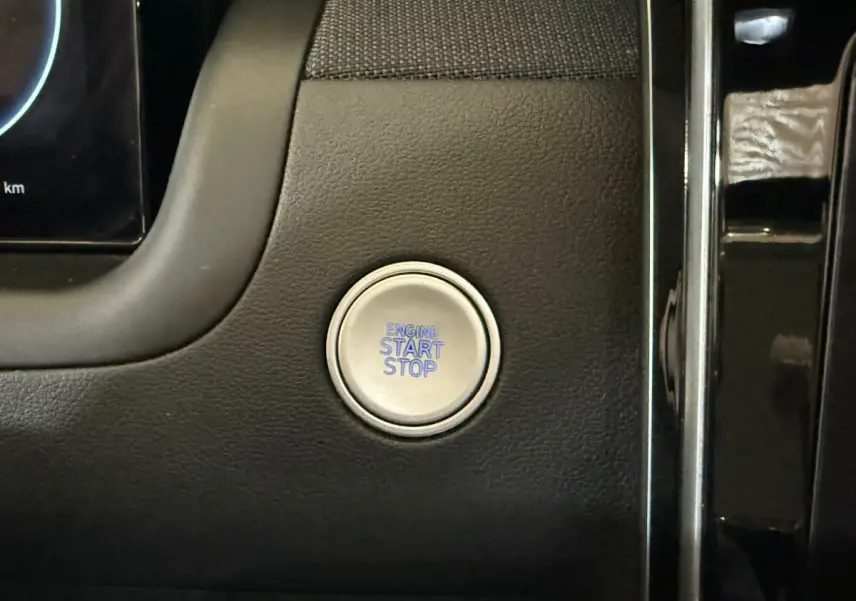 Bouton démarrage moteur circulaire argenté sur tableau de bord noir du Hyundai Tucson hybride 2021.