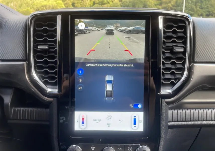 Vue du tableau de bord du Ford Ranger 2025 avec écran central tactile affichant caméra de recul et commandes climatisation.