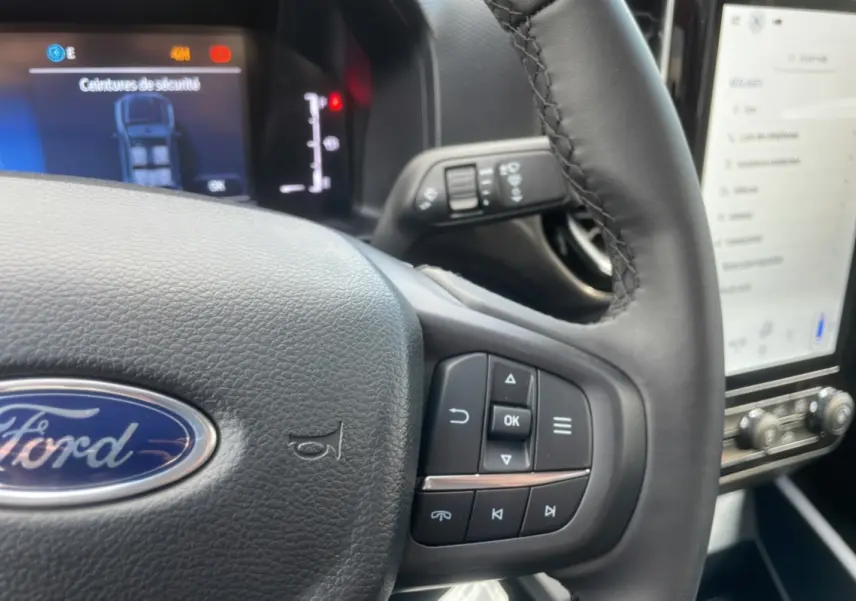 Vue rapprochée du volant Ford Ranger rouge racing 2025 avec commandes multifonctions et tableau de bord numérique.