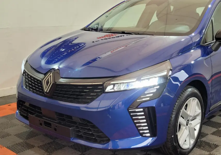 Vue 3/4 avant droite d'une Renault Clio bleu avec phares LED et calandre noire distinctive.