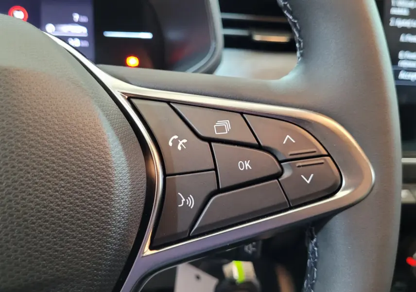 Gros plan sur les commandes multifonctions du volant cuir noir de la Renault Clio Evolution Blue dCi 100 2025.