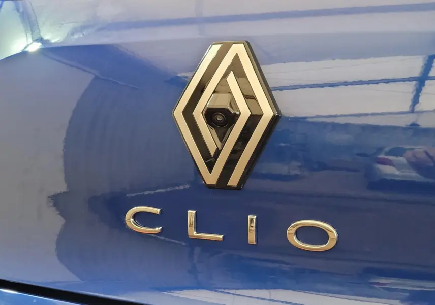 Gros plan sur le logo Renault et le nom Clio sur la malle arrière bleu vif d'une Clio Evolution 2025.