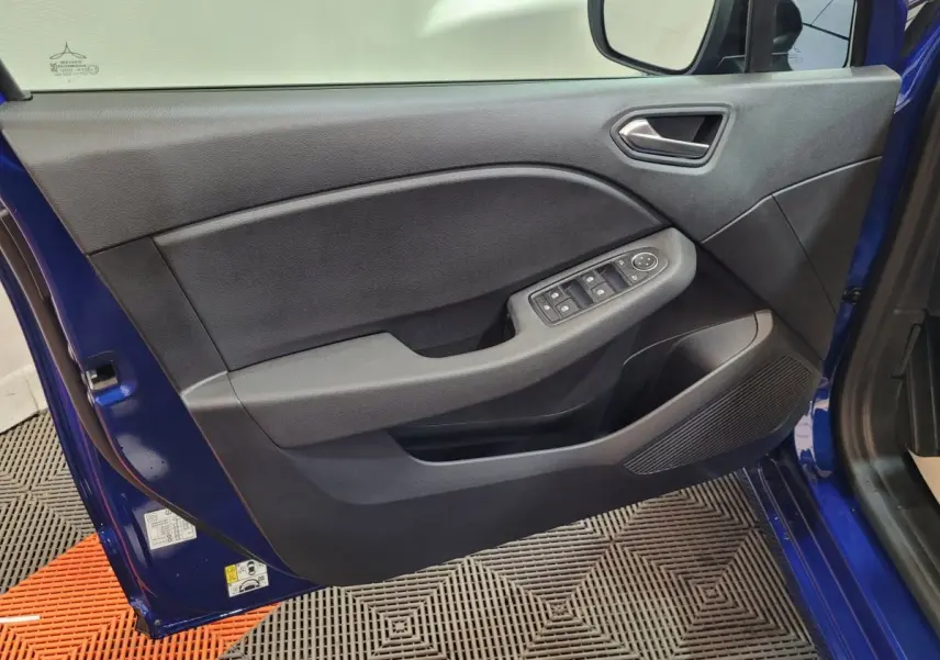 Porte avant gauche ouverte d'une Renault Clio bleu 2025, avec commandes électriques des vitres et haut-parleur intégré.