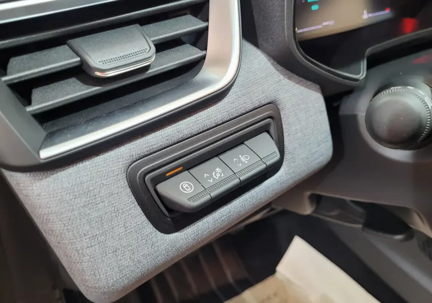 Gros plan sur les commandes d'éclairage et verrouillage à gauche du tableau de bord intérieur de la Renault Clio bleu 2025.