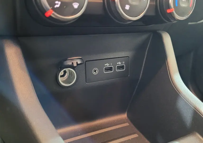 Gros plan sur la console centrale noire de la Renault Clio Evolution Blue dCi 100, montrant prises USB et allume-cigare.