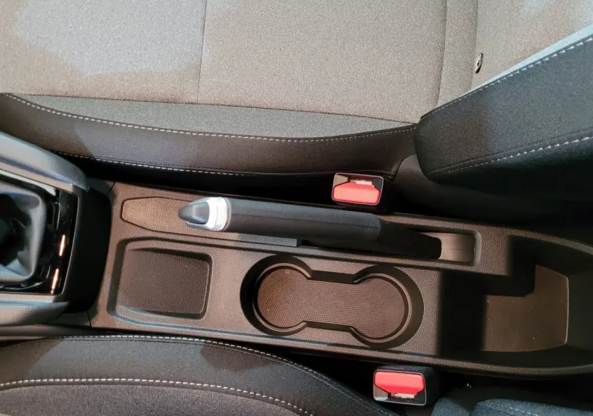 Vue en plongée sur la console centrale noire de la Renault Clio Evolution Blue dCi 100 avec frein à main manuel et porte-gobelets.