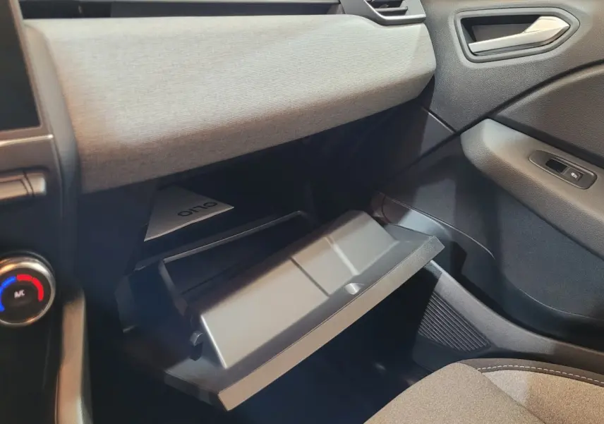 Intérieur de la Renault Clio 2025 bleu, vue côté passager sur la boîte à gants ouverte et tableau de bord gris clair.