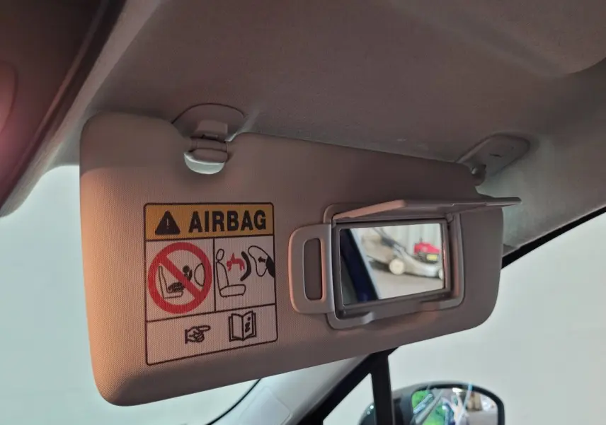 Détail du pare-soleil côté conducteur avec miroir et avertissement airbag dans une Renault Clio bleu 2025.