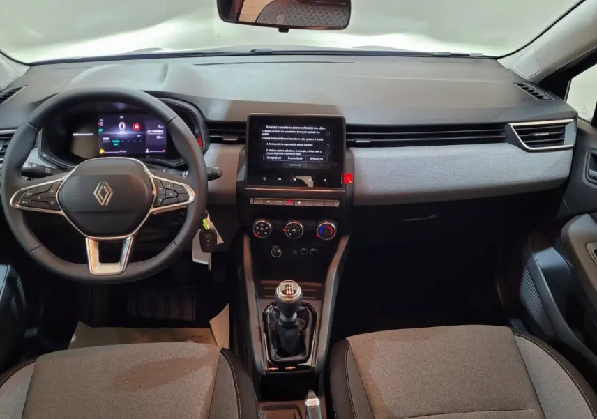 Intérieur de la Renault Clio 2025, vue de face sur le tableau de bord avec écran tactile et volant cuir multifonctions.
