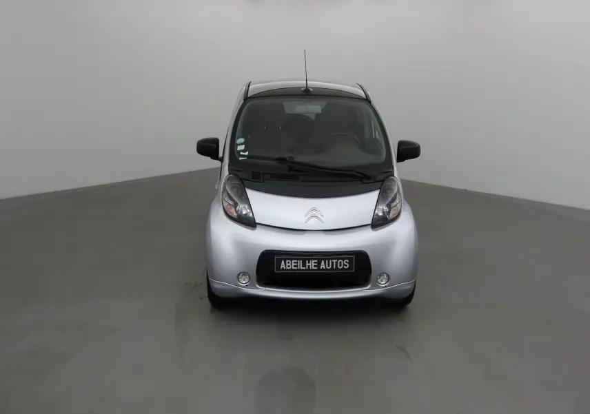 Vue frontale d'une Citroën C-ZERO gris alu 2018 avec phares arrondis et plaque Abeilhe Autos visible.