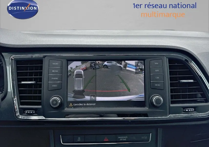 Écran central du SEAT Ateca blanc montrant la caméra de recul avec guidage de trajectoire en ville.