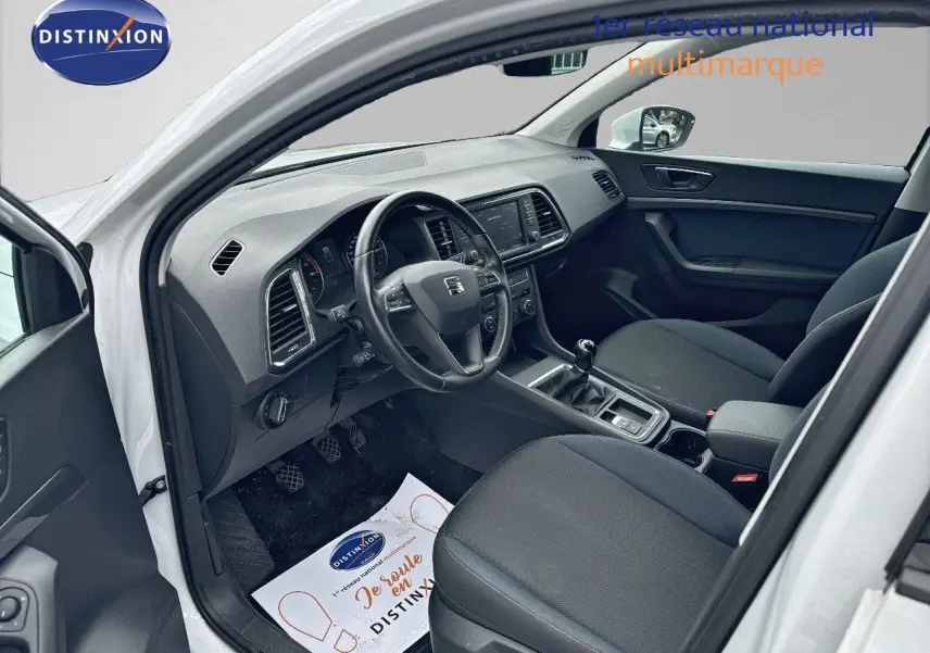 Vue intérieure côté conducteur du SEAT Ateca blanc Nevada 2018, montrant tableau de bord et sièges noirs.