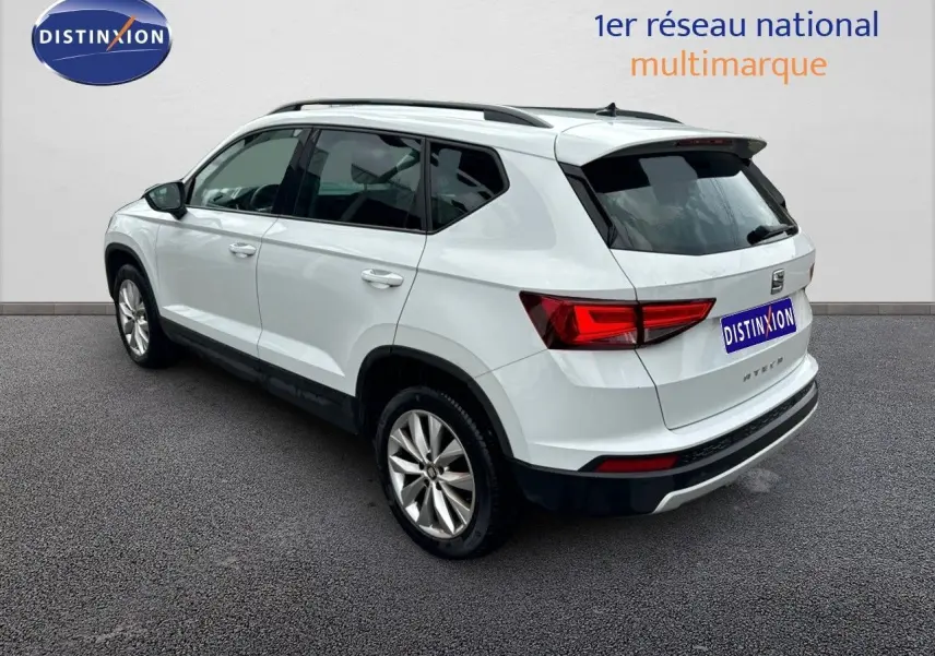 SEAT Ateca blanc Nevada en vue 3/4 arrière côté gauche, avec feux arrière LED et jantes alliage visibles.