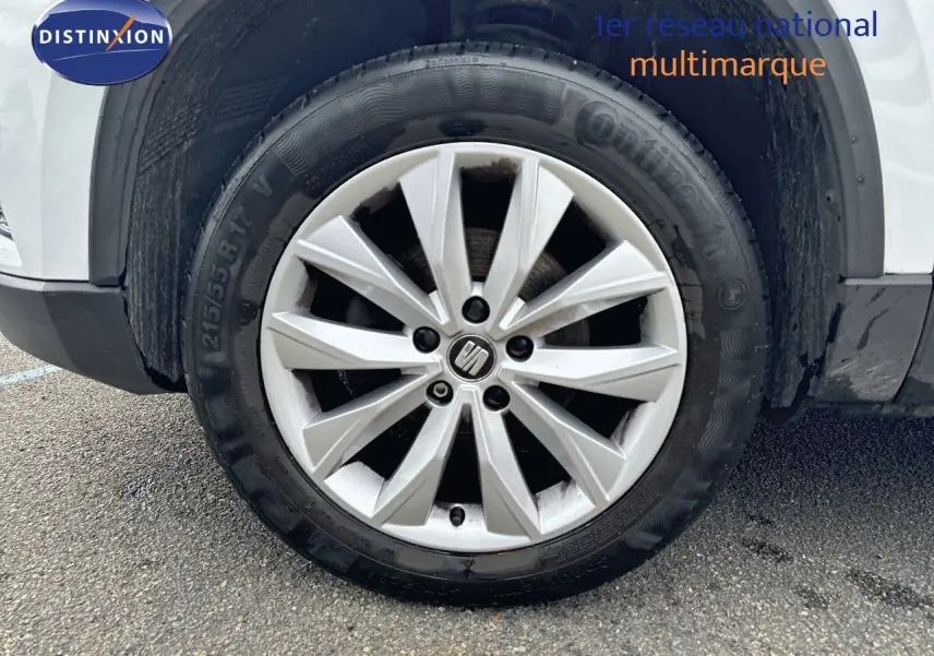 Gros plan sur la roue avant gauche du SEAT Ateca blanc Nevada, mettant en valeur la jante en alliage au design moderne.