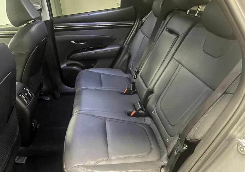 Vue côté droit des sièges arrière en cuir noir du Hyundai Tucson 2023 gris, avec appuie-têtes réglables et ceinture de sécurité.