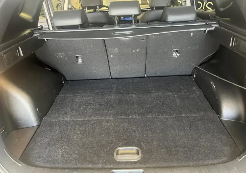Coffre ouvert du Hyundai Tucson gris 2023, vue intérieure arrière montrant la plage arrière et les sièges rabattus.