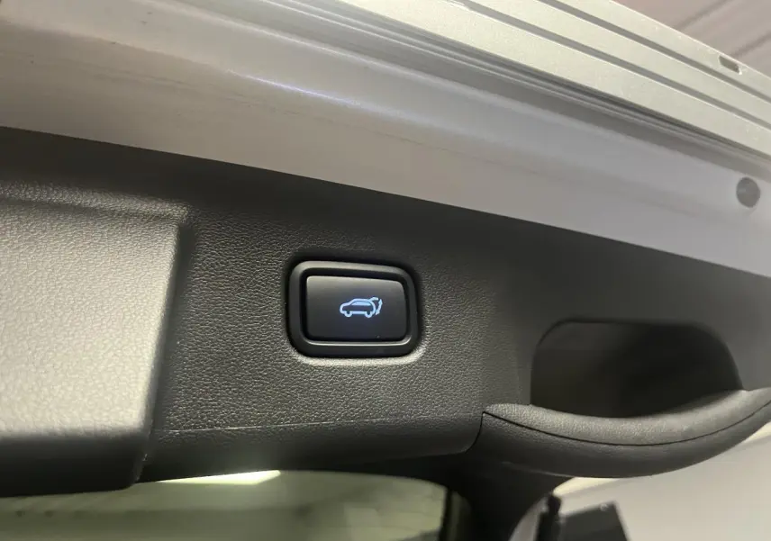 Bouton d'ouverture électrique du hayon sur le bord intérieur du coffre du Hyundai Tucson gris 2023.