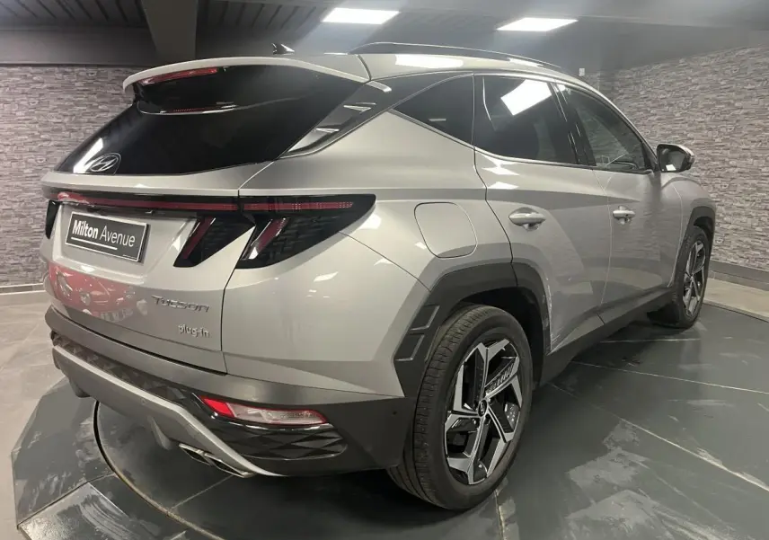 Vue 3/4 arrière droite du Hyundai Tucson gris métallisé avec feux arrière à LED et jantes alliage 19 pouces.