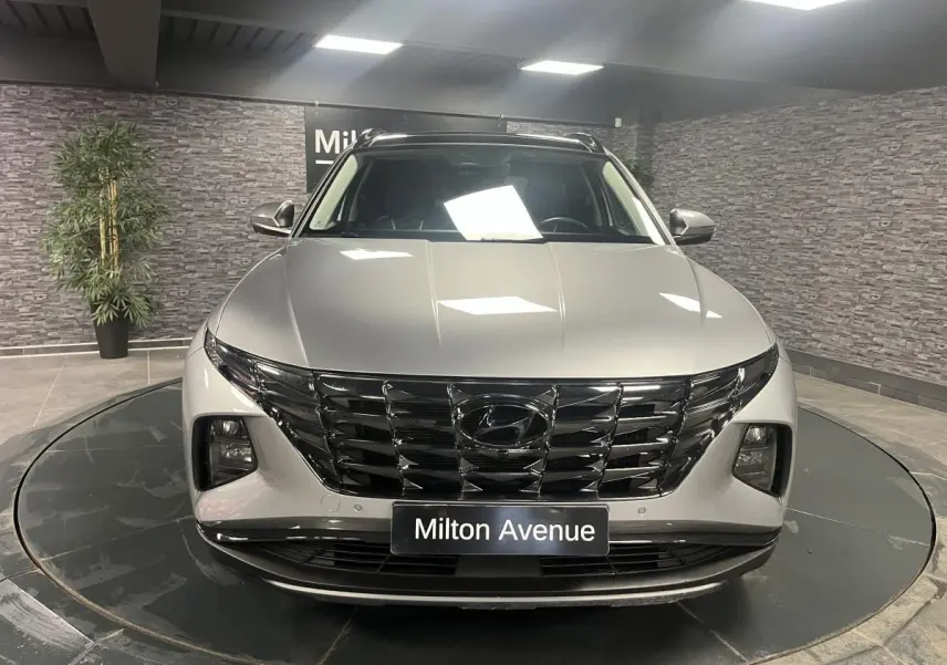 Vue avant d'un Hyundai Tucson gris métallisé 2023 avec calandre noire brillante et feux LED intégrés.