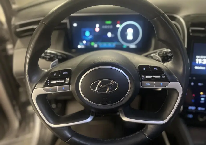 Vue rapprochée du volant cuir noir avec commandes intégrées du Hyundai Tucson gris 2023 hybride rechargeable.