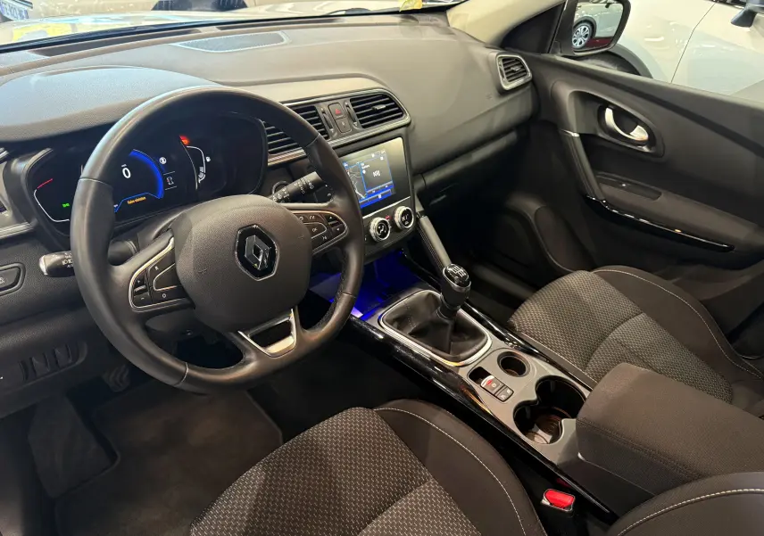 Vue intérieure côté conducteur du Renault Kadjar 2020, tableau de bord noir avec volant multifonction et levier de vitesse manuel.
