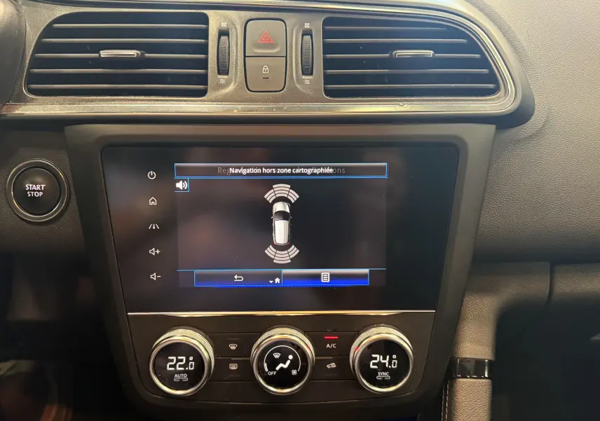 Vue rapprochée de la console centrale du Renault Kadjar 2020, écran tactile avec capteurs de stationnement et commandes climatisation.