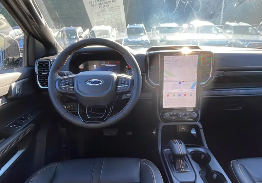Vue intérieure frontale du Ford Ranger 2025 gris iconic, mettant en valeur le volant multifonction et l'écran tactile vertical central.