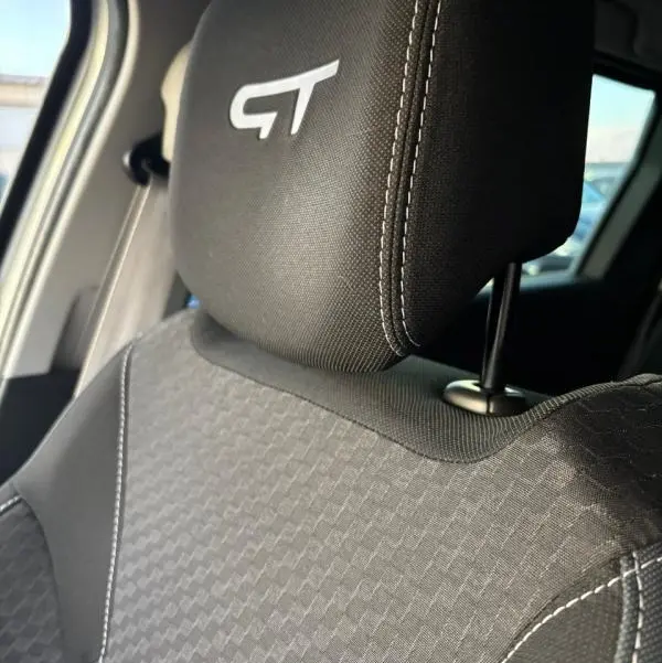 Gros plan sur l'appui-tête avant gauche brodé GT et le tissu gris à motifs du siège Renault Clio IV Estate TCe 120 GT EDC.