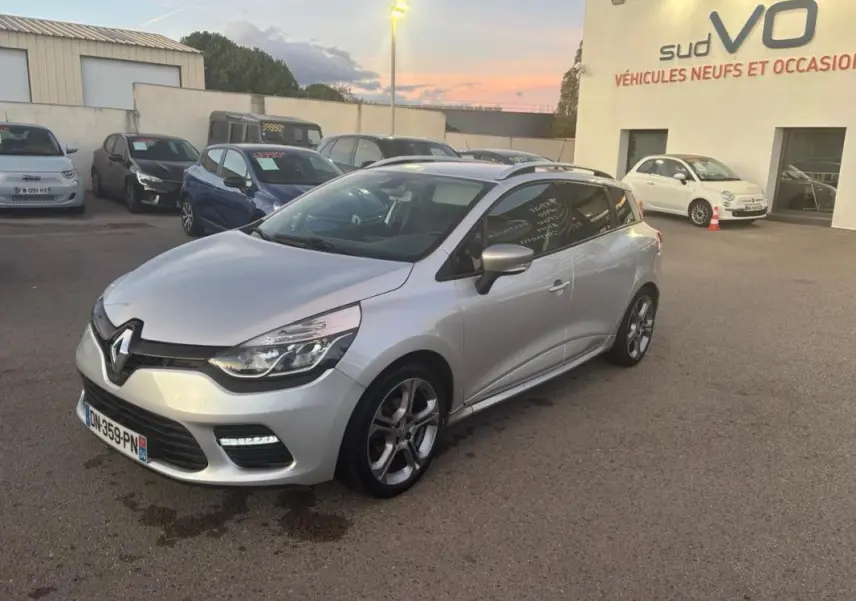 Renault Clio IV Estate gris clair vue 3/4 avant droit, jantes alliage 17 pouces et vitres surteintées visibles.