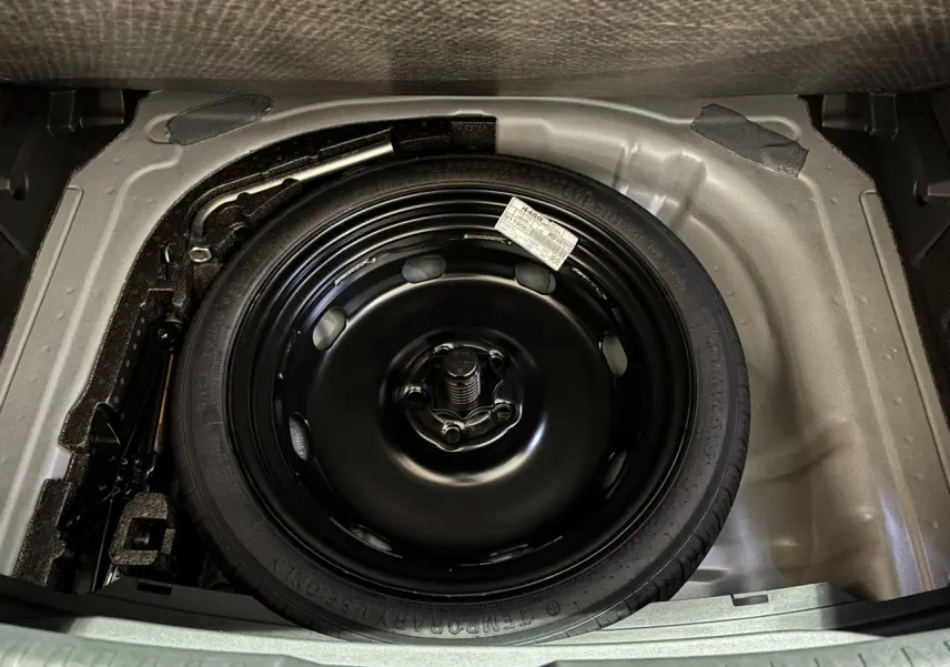 Vue plongeante sur la roue de secours noire dans le coffre d'une CUPRA Leon Gris Graphène 2026.
