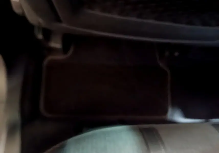 Détail du tapis de sol et partie inférieure du siège avant dans l’habitacle sombre d’un Peugeot 3008 gris foncé.