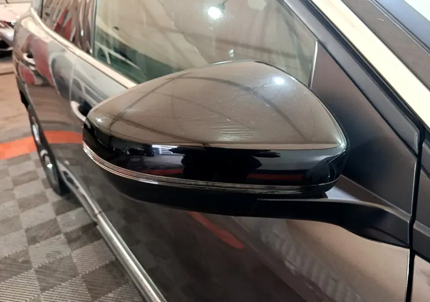 Gros plan sur le rétroviseur côté gauche du Peugeot 3008 gris foncé, avec clignotant intégré et carrosserie brillante.