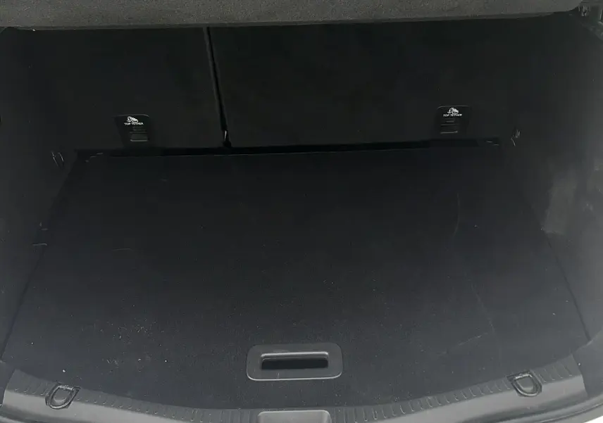 Coffre ouvert vu de l'arrière d'un Renault Scenic IV blanc nacré avec intérieur noir, espace de chargement vide.
