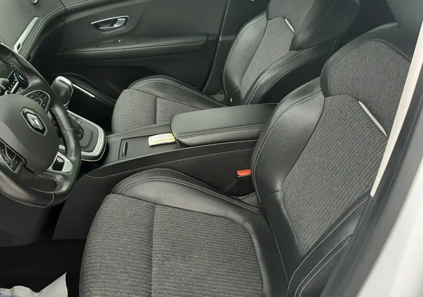 Vue intérieure côté conducteur du Renault Scénic IV 1.3 TCE 140 Intens avec sièges tissu et cuir noir, volant multifonction et console centrale.