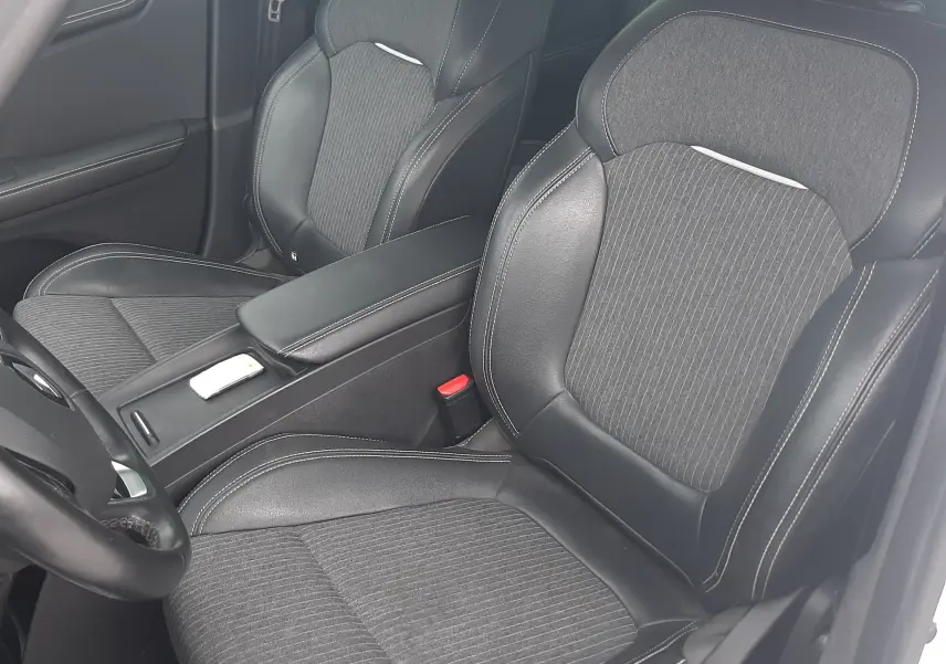 Vue intérieure rapprochée des sièges avant en tissu et cuir noir du Renault Scénic IV blanc nacré avec toit noir.