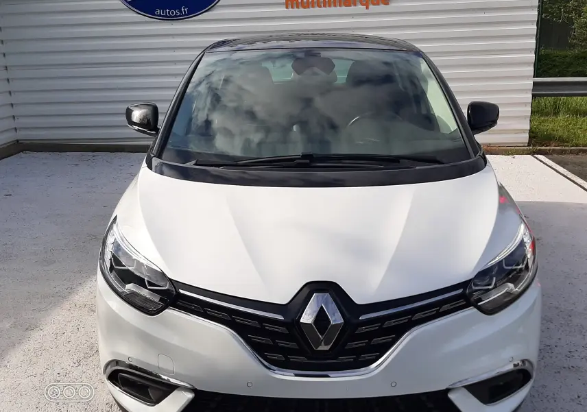 Vue avant d’un Renault Scénic IV blanc nacré avec toit noir, calandre noire et plaque "OCCASION" visible.