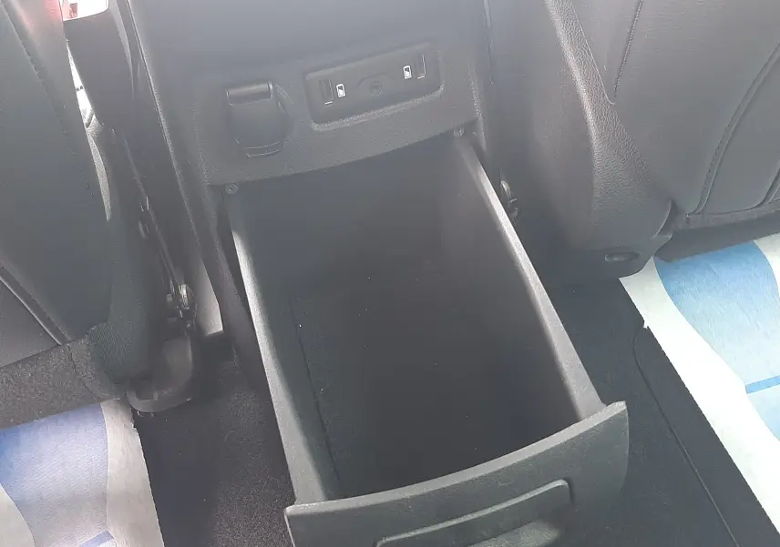 Gros plan sur le rangement ouvert entre les sièges arrière d’un Renault Scenic IV, intérieur noir.