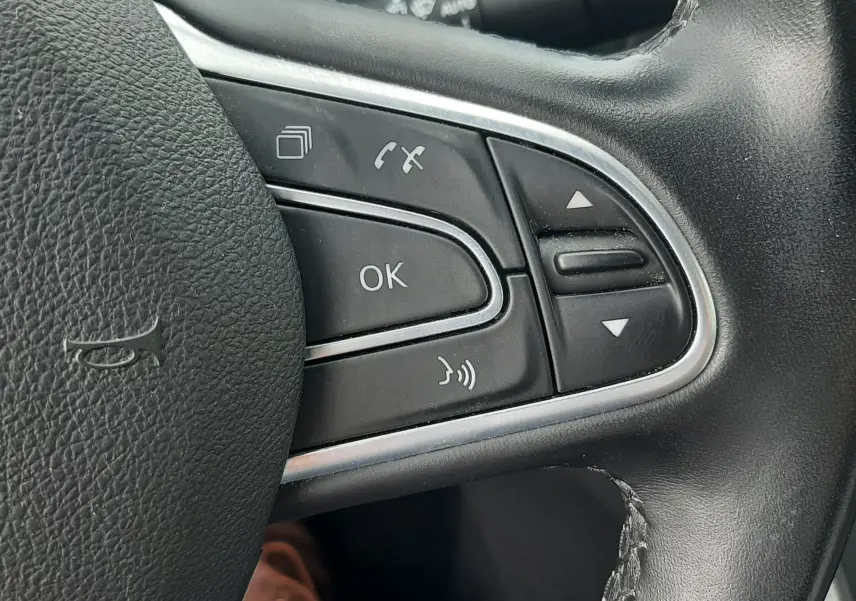 Gros plan sur les commandes multifonctions noires du volant cuir du Renault Scénic IV blanc nacré, version 2021.