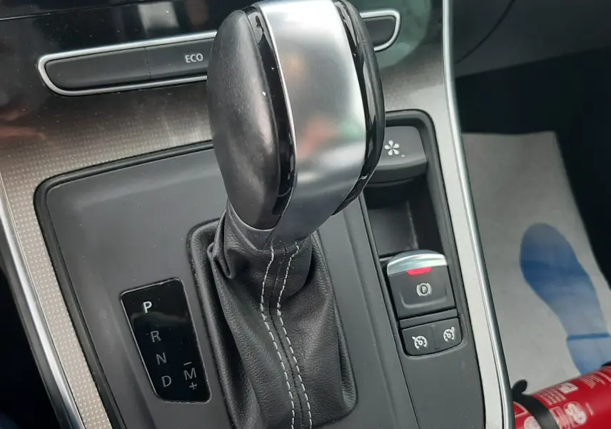 Gros plan sur le levier de vitesses automatique noir et argenté du Renault Scénic IV, avec console centrale et bouton frein à main visible.
