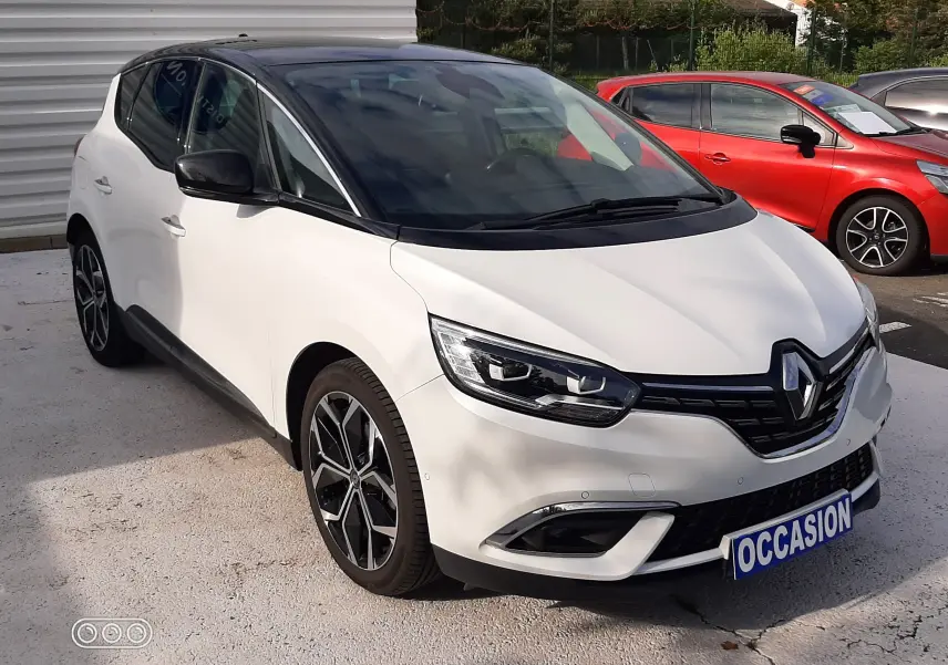 Renault Scénic IV blanc nacré avec toit noir, vue 3/4 avant droit, jantes alliage et plaque "OCCASION" visible.
