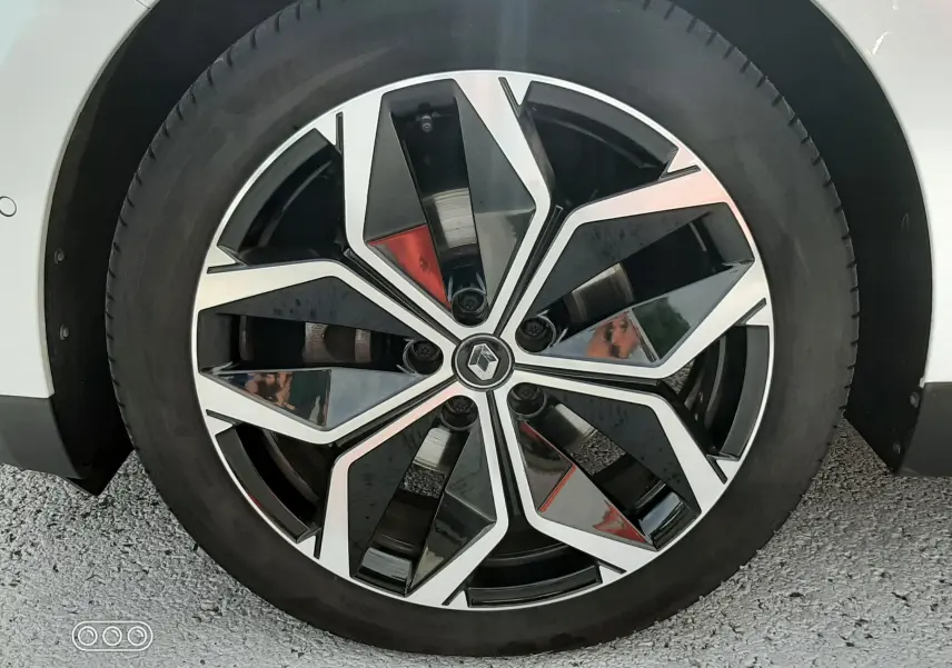 Gros plan sur la roue avant droite du Renault Scénic IV blanc nacré avec jante alliage diamantée noire et argent.