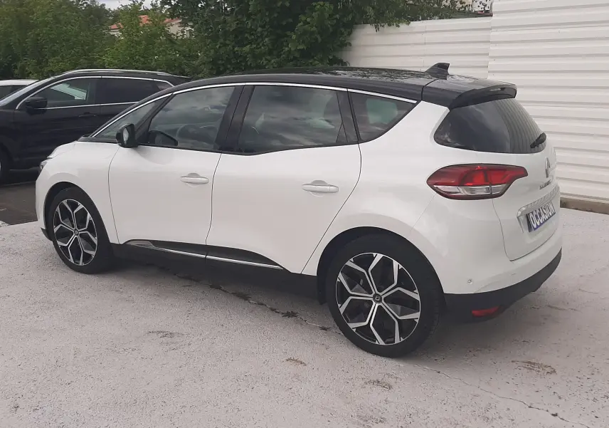 Renault Scénic IV blanc nacré avec toit noir, vue 3/4 arrière droit, jantes alliage distinctives, stationné en extérieur.