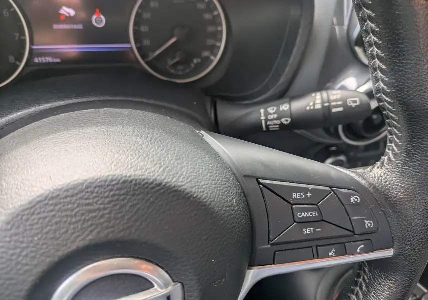 Vue rapprochée du volant noir du Nissan Juke rouge 2020, avec commandes de régulateur de vitesse visibles.
