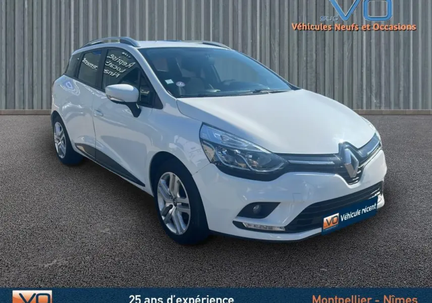 Renault Clio IV Estate Business blanche vue 3/4 avant droit, avec vitres surteintées et feux diurnes LED visibles.
