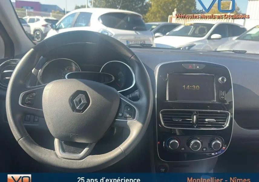 Vue intérieure du tableau de bord et volant cuir Renault Clio IV Estate Business blanc, avec écran central et commandes de climatisation.