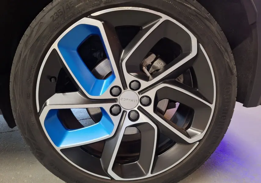 Gros plan sur la jante avant droite du Lynk & Co 01 PHEV 2022, avec inserts bleus et peinture noire métallisée.